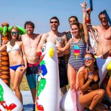 Smiling men and women in swimsuits pose with inflatables