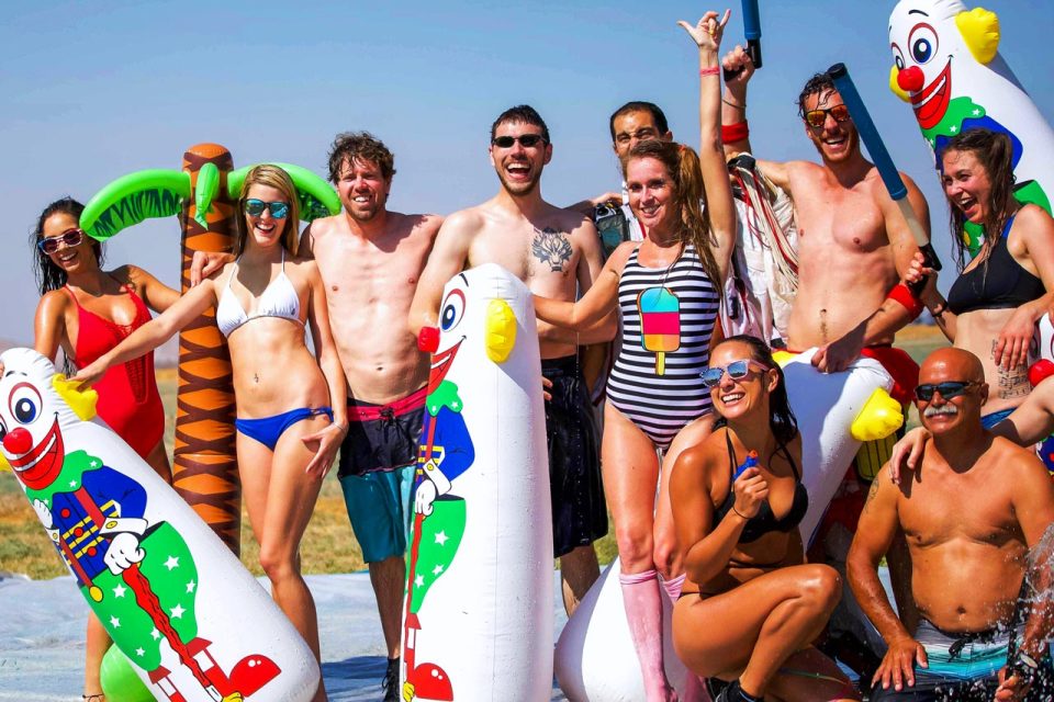 Smiling men and women in swimsuits pose with inflatables