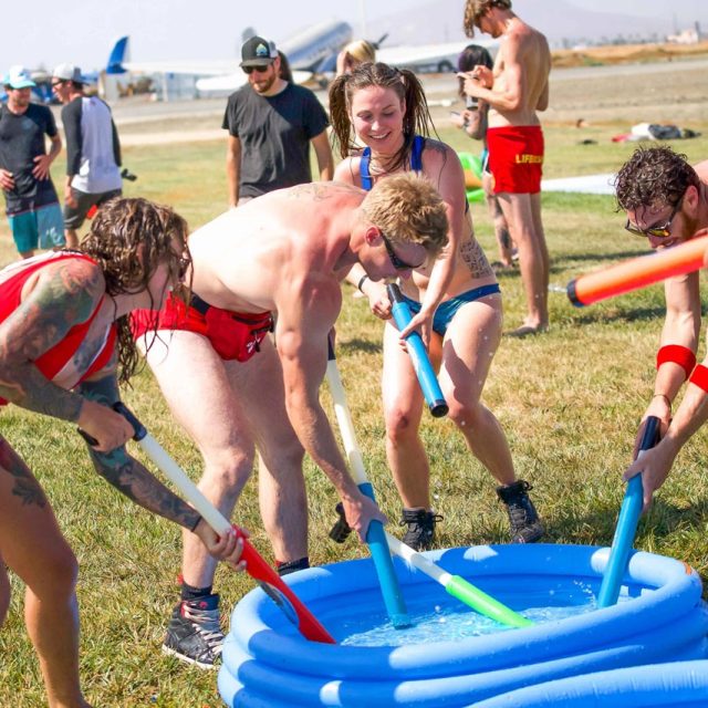 Several people in swimsuits play with water shooters