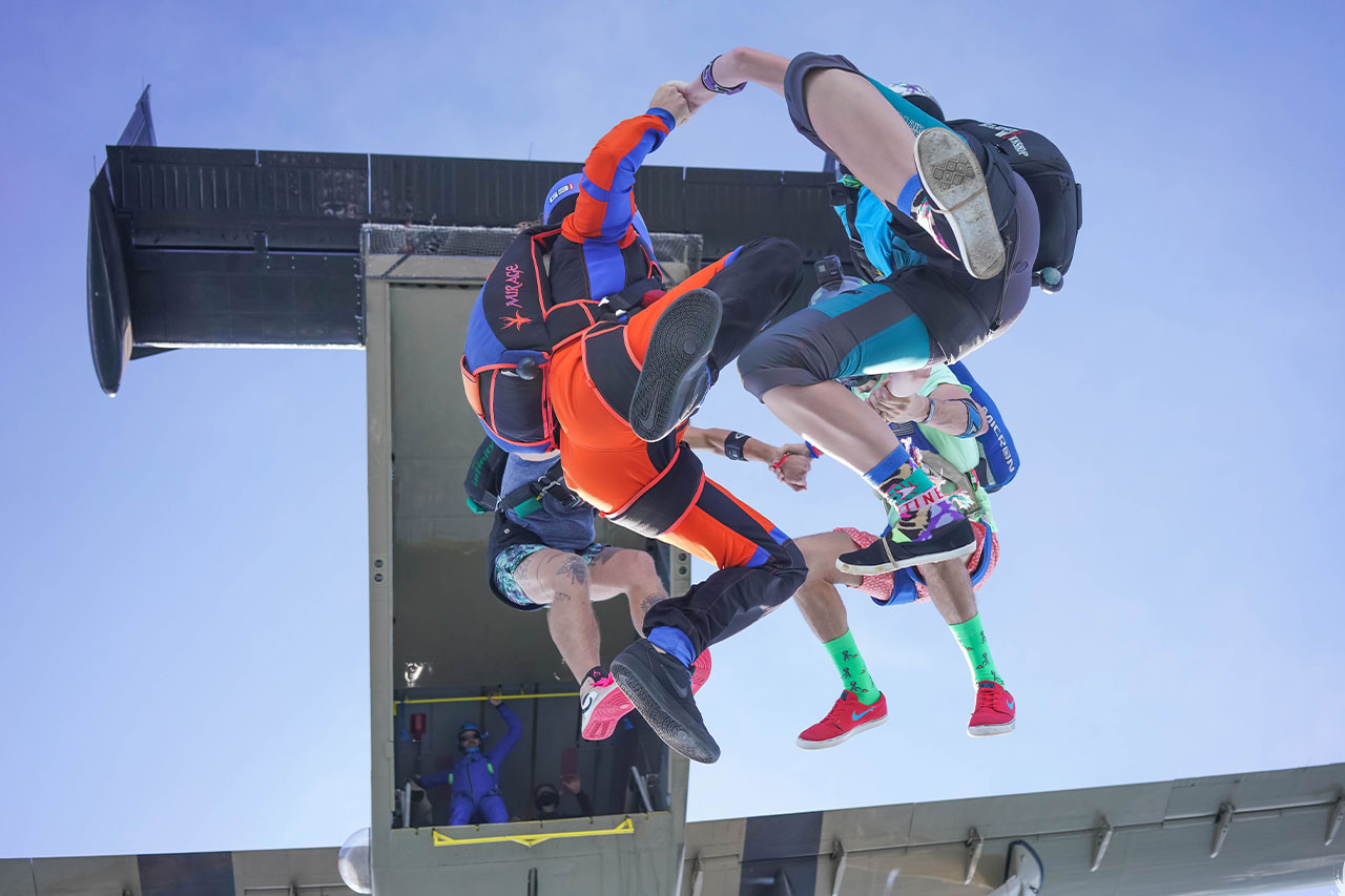 Group of four experienced skydivers in formation after exiting an airplane