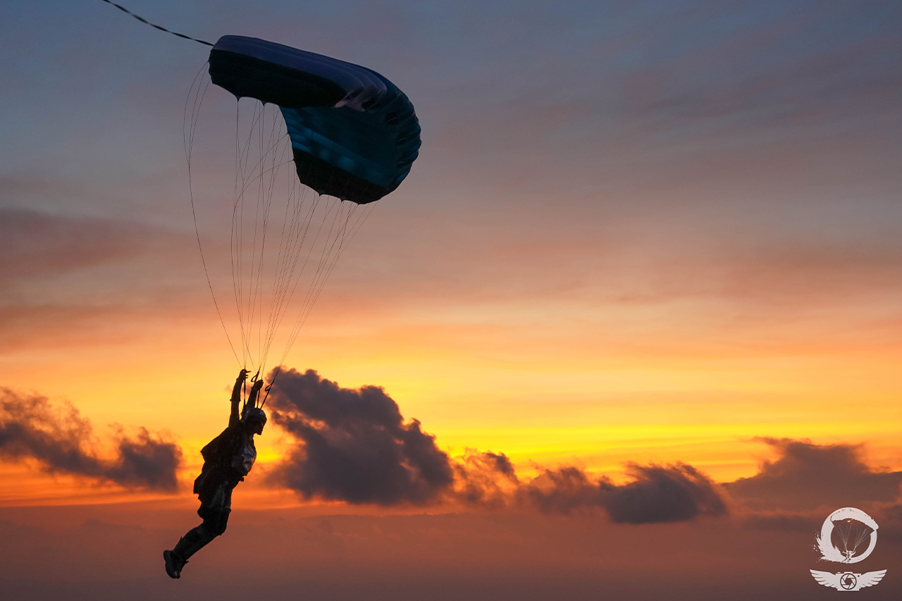 Licensed skydiver under canopy at sunset