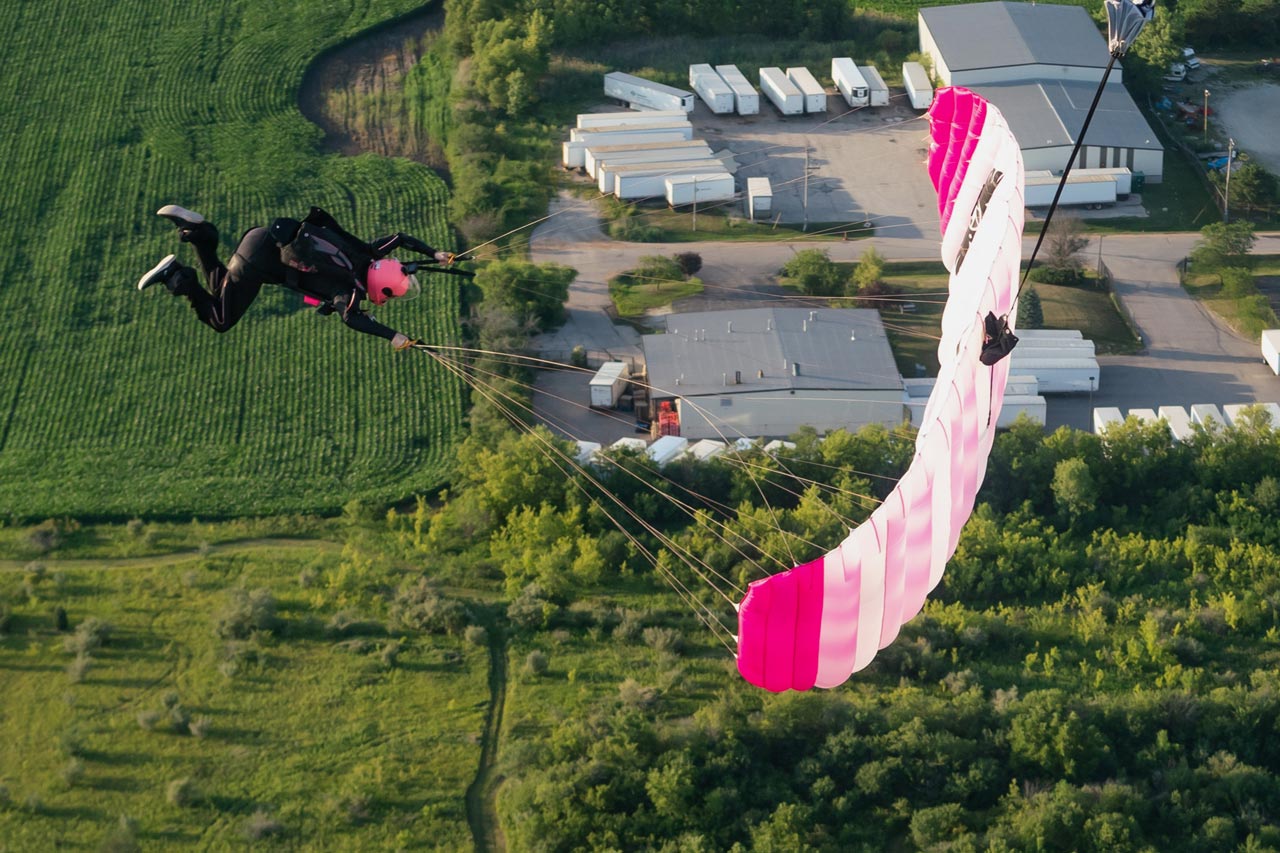 Experienced skydiver flying a pink and white canopy preparing to land