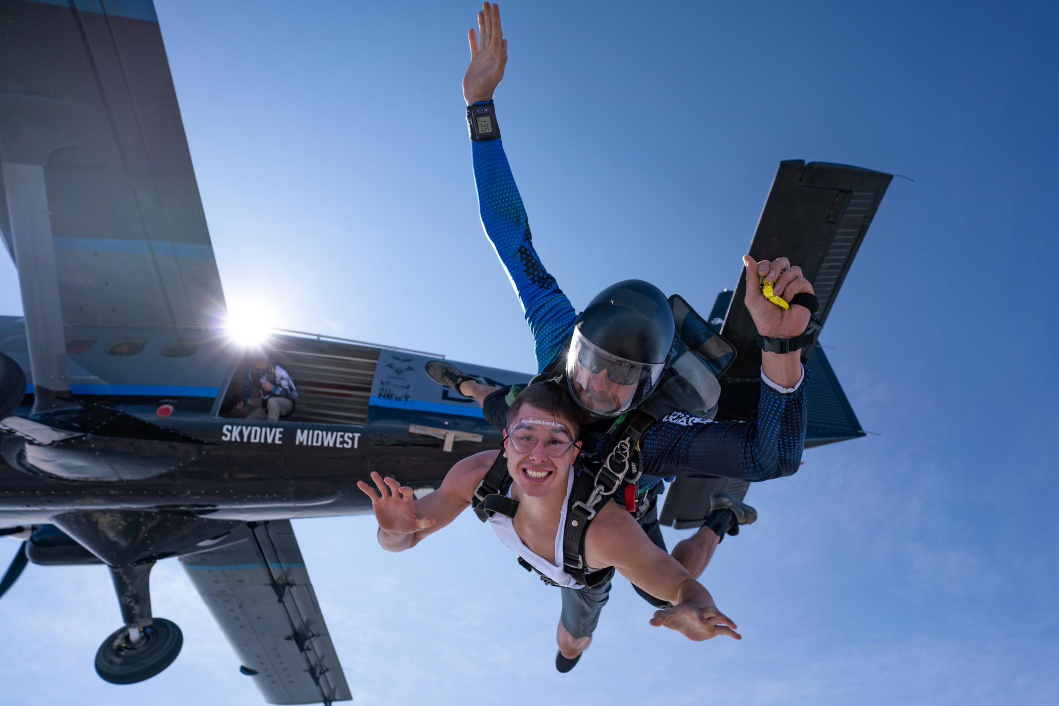 Tandem skydiving student and instructor in freefall with plane in the background