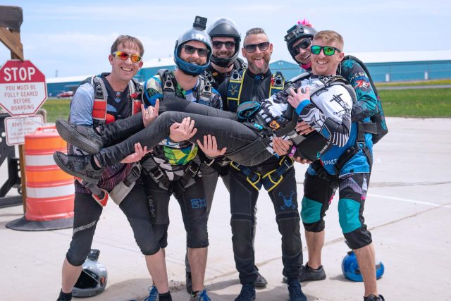 Group of experienced male skydivers posing for a photo on the runway
