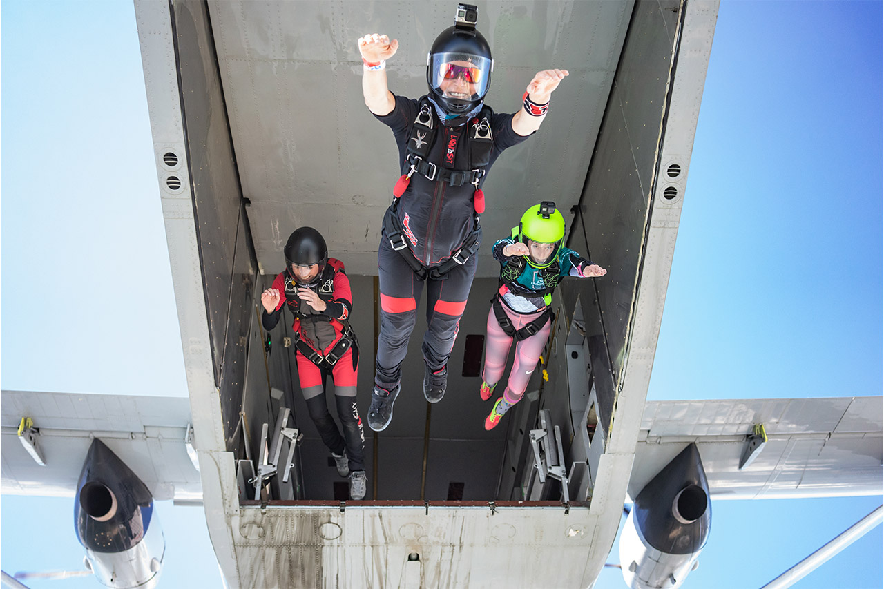 Three experienced skydivers exiting the back of an airplane