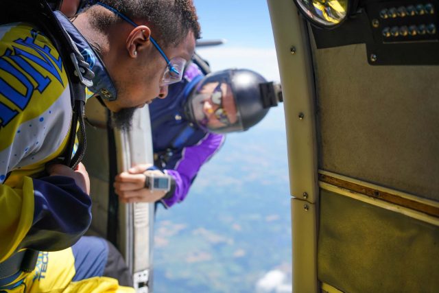 Tandem skydiving student approaching the door of an airplane in preparation for jumping