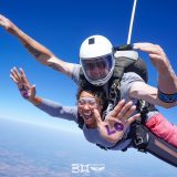 Female tandem skydiving student in freefall with YOLO written on her palms
