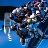 A group of licensed skydivers exiting an airplane in formation
