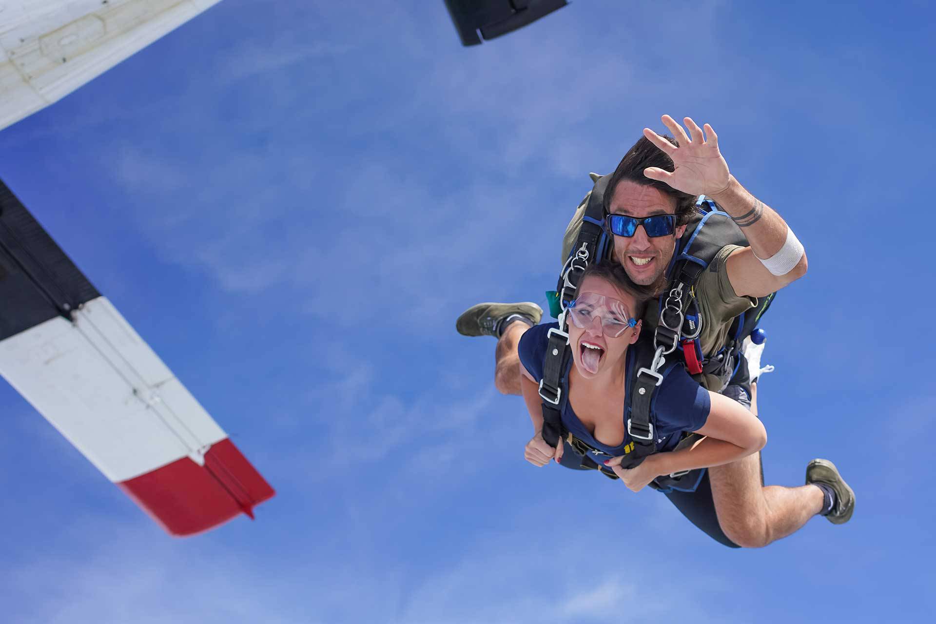 Female tandem skydiving student sticking out her tongue in freefall