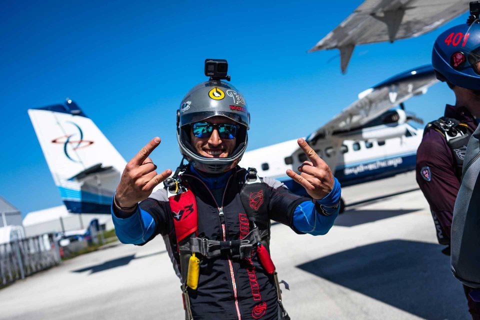 Licensed skydiver preparing to board aircraft giving rock on sign with hands